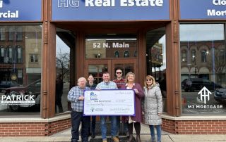 HG Real Estate Garrett Hall and Jenny Koski displaying their donation of $10,000 to the Three Rivers Promise