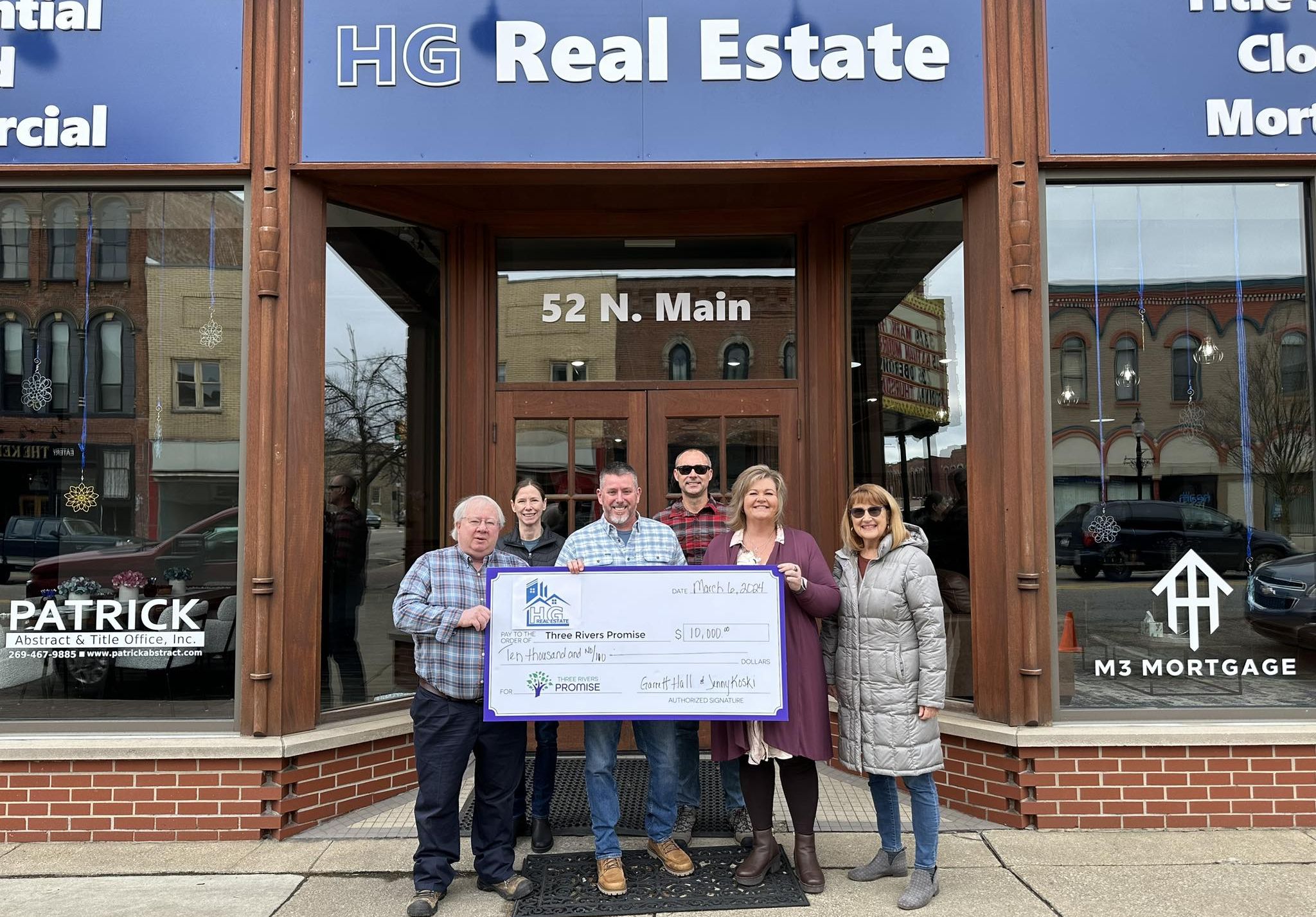 HG Real Estate Garrett Hall and Jenny Koski displaying their donation of $10,000 to the Three Rivers Promise